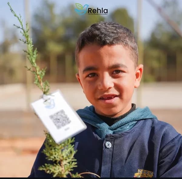 طالب يحمل شتلة غرسة موثقة برمز QR